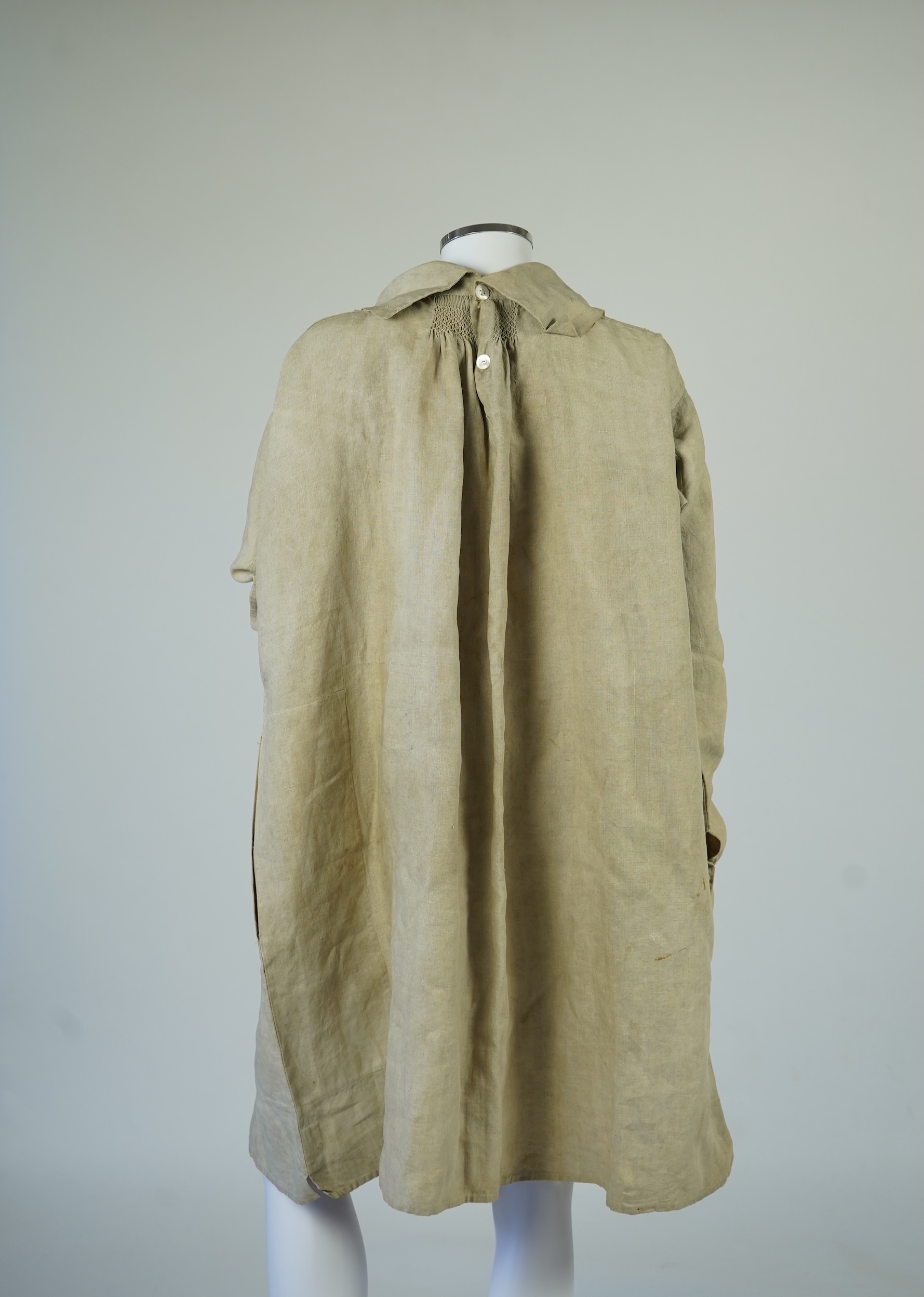 A 19th century heavy linen Shepherd’s smock, with small smocked shoulders and front and back neck panels under collar., 97cm long. Condition - patched and small darn near top and minor wear, usual for age and use.